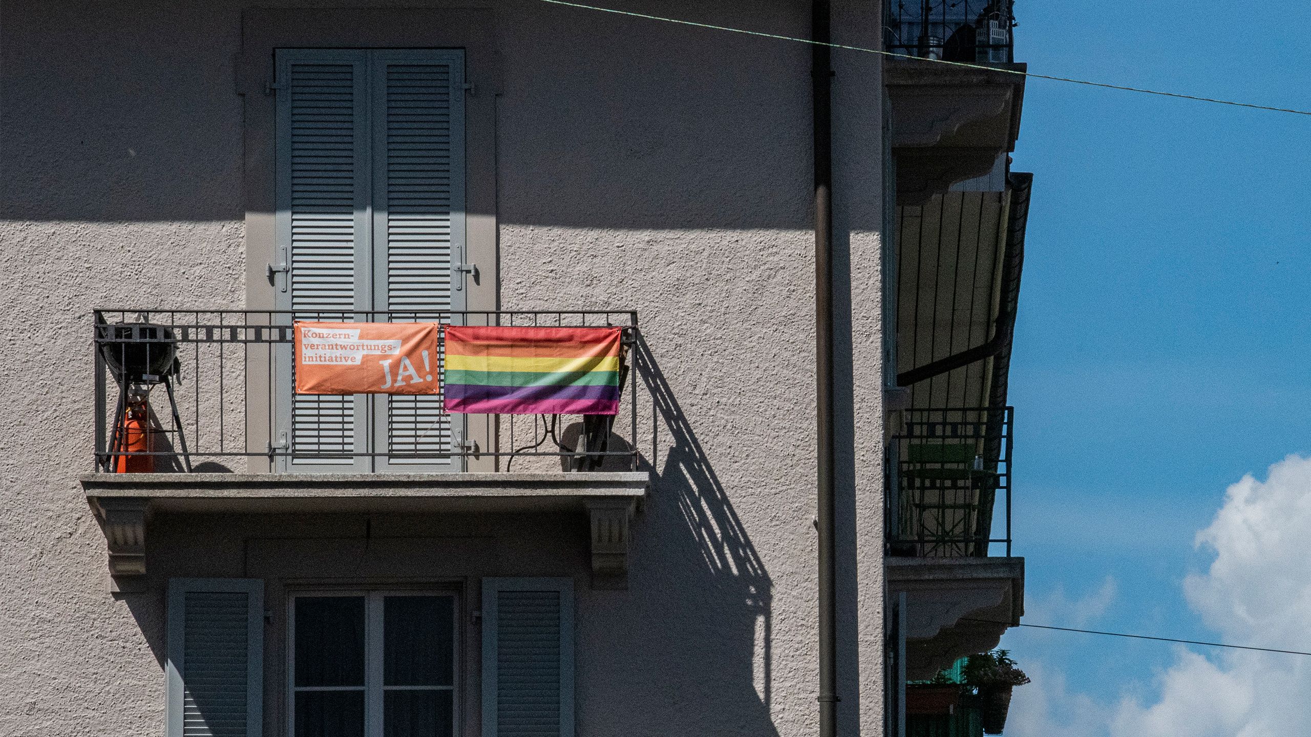 An orange flag with the inscription "Yes to the Responsible Business Initiative" hangs on a balcony.