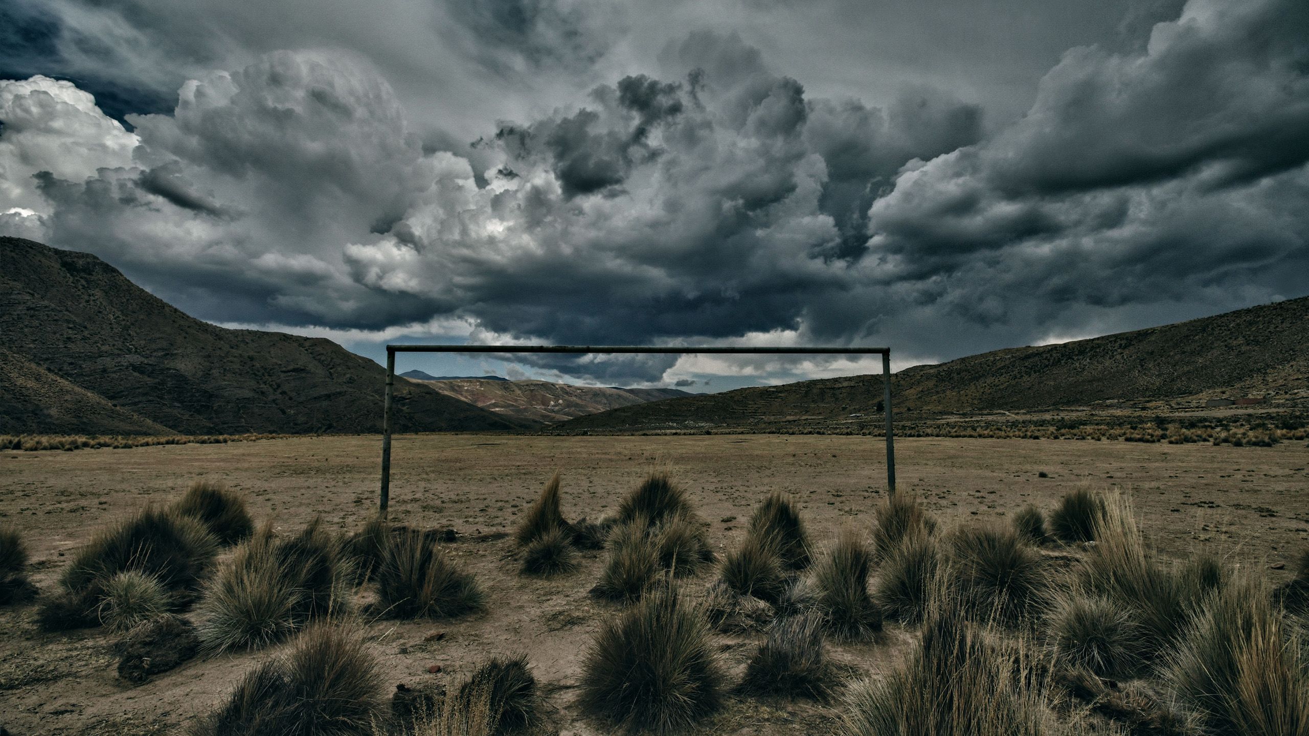 Eine dramatische Landschaftsaufnahme mit karger Berglandschaft und gewittrigen Wolken.