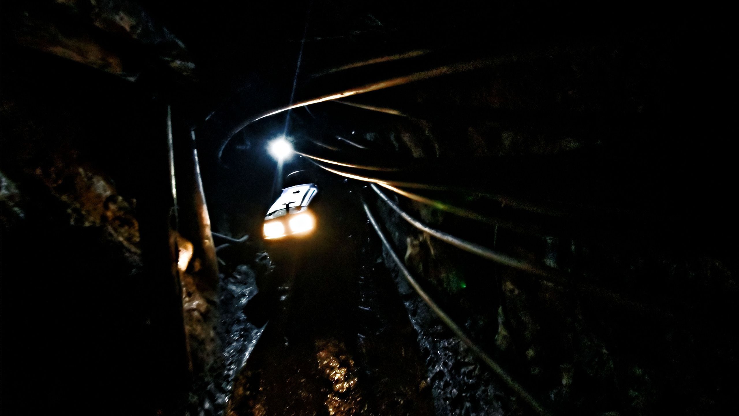 Les phares d’un tracteur surgissent au fond d’un tunnel étroit et sombre.